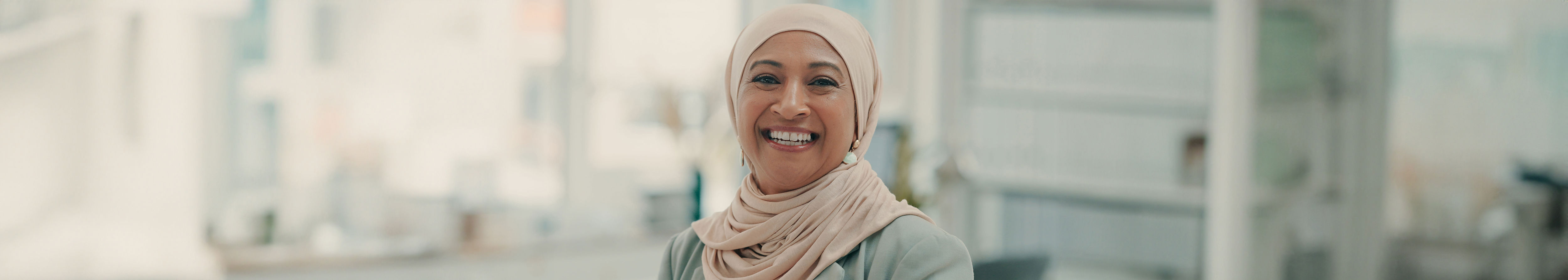 Smiling Arabic woman with cream coloured Hijab top.
