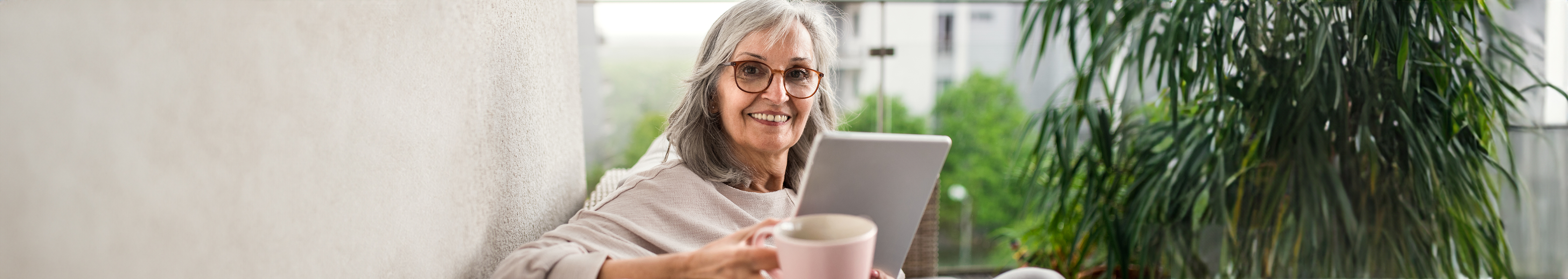 Happy elderly woman smiling and holding a cup.