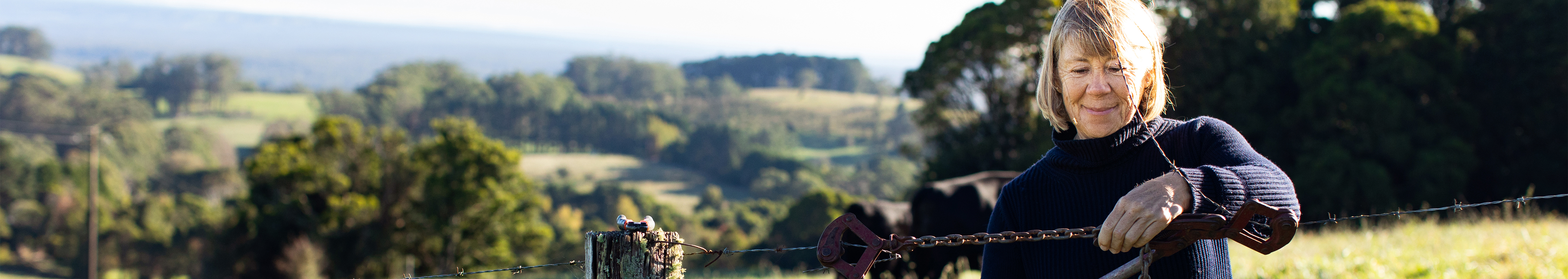 A woman smiling in a rural area background.