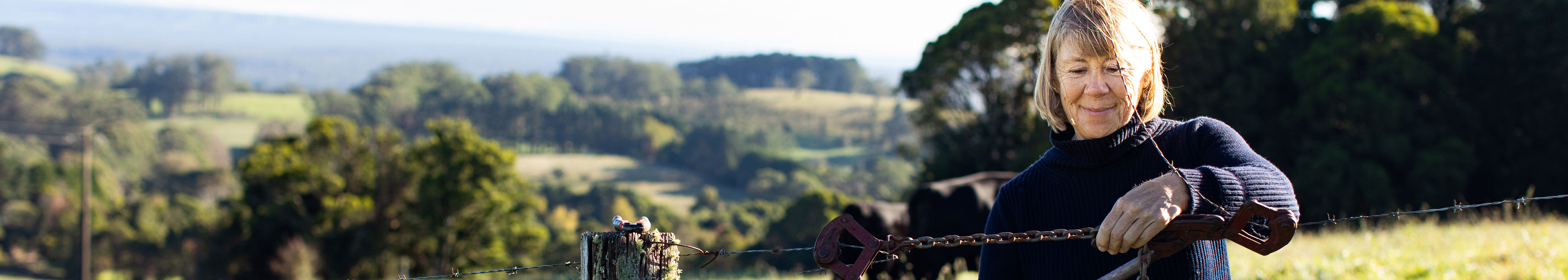 A woman smiling in a rural area background.