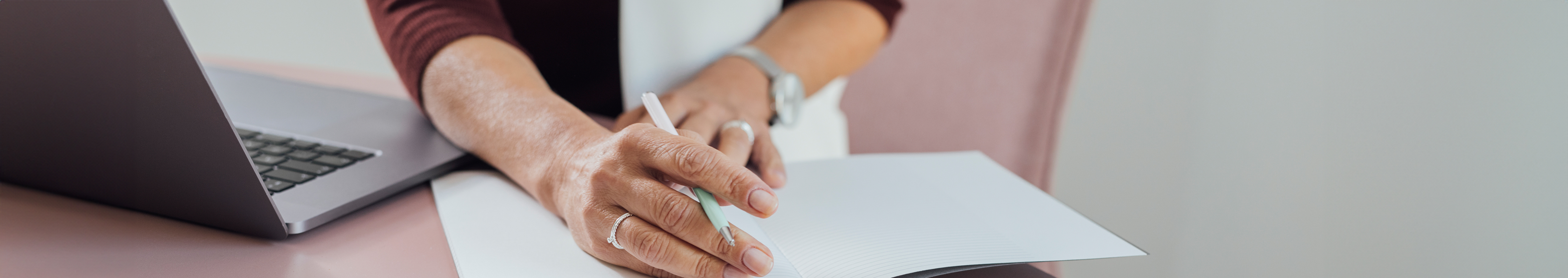 A woman's hand on a notebook with a pen