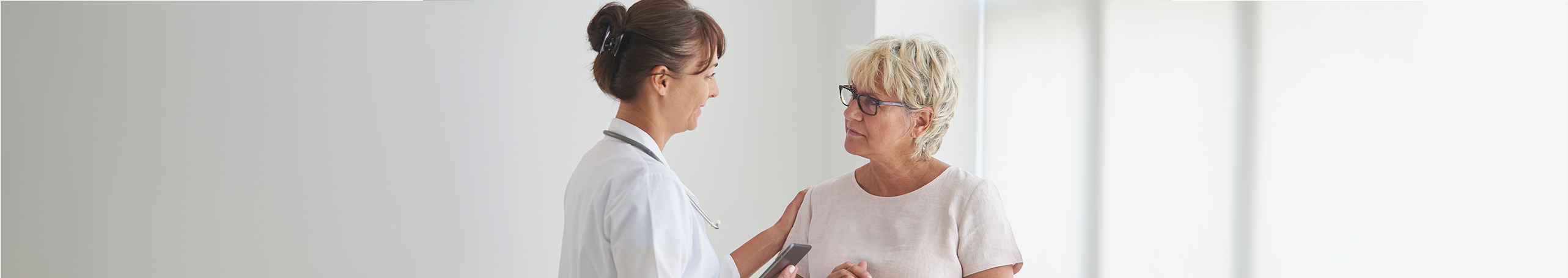 An elderly woman is consulting with a Doctor in a clinic room.