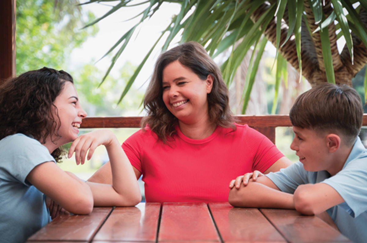 A happy woman with two kids on a table.