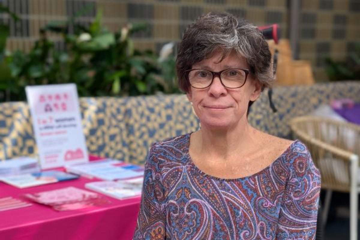 woman with glasses sitting at a table with a pink tablecloth